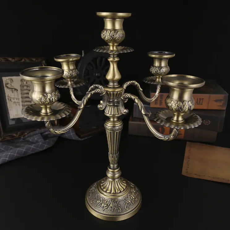 Bronze candelabrum on a dark surface with books and a photo frame in the background
